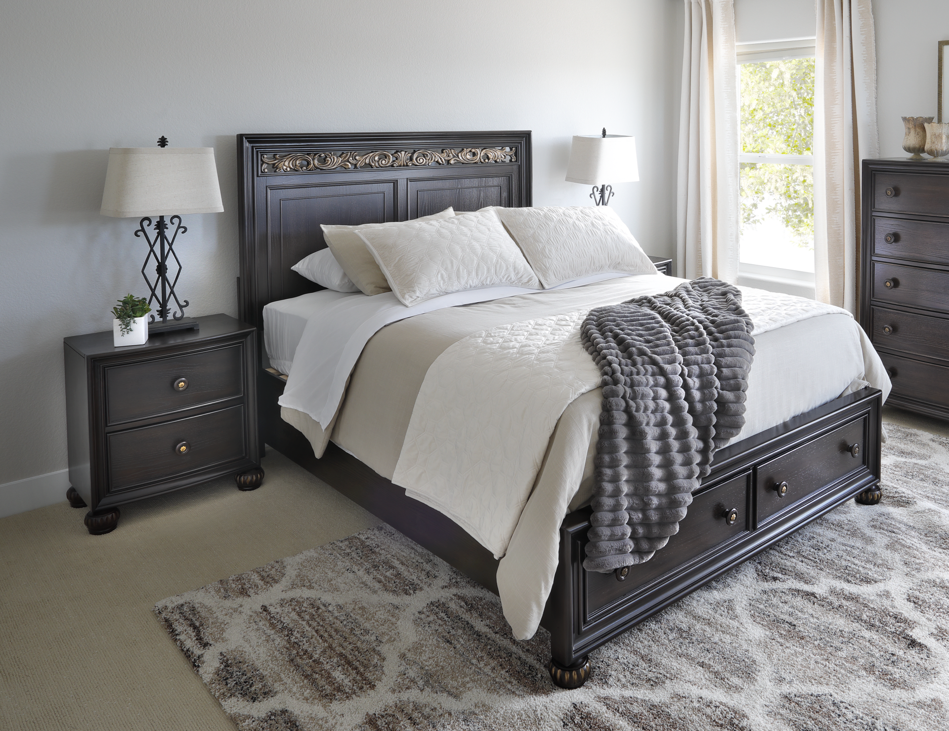 Deep brown traditional style bed with footboard storage accompanied by nightstands in bedroom window scene