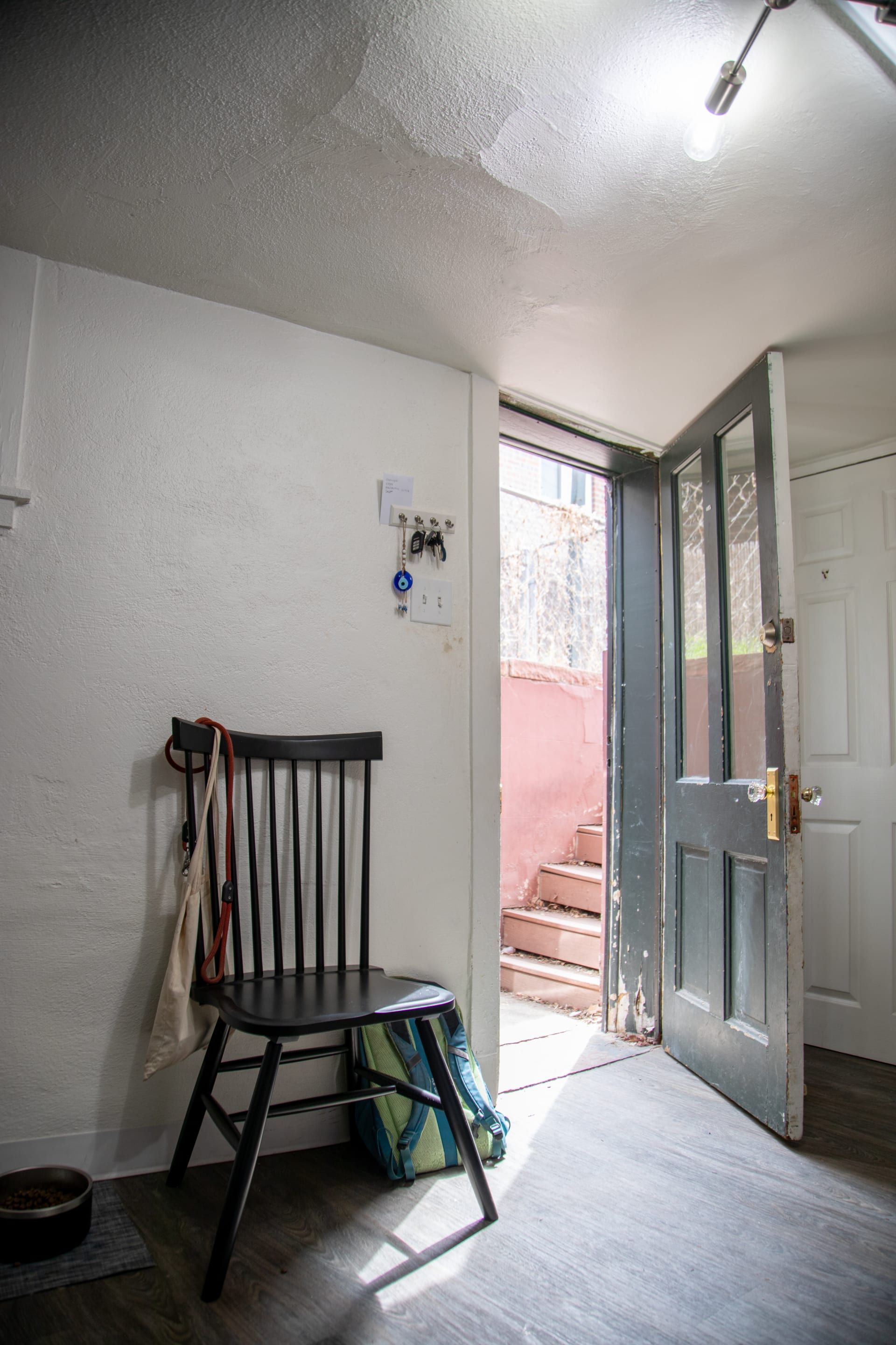 The La Paz Dining Chair styled by Mackinley's apartment front door, which can also double as shoe storage or extra seating