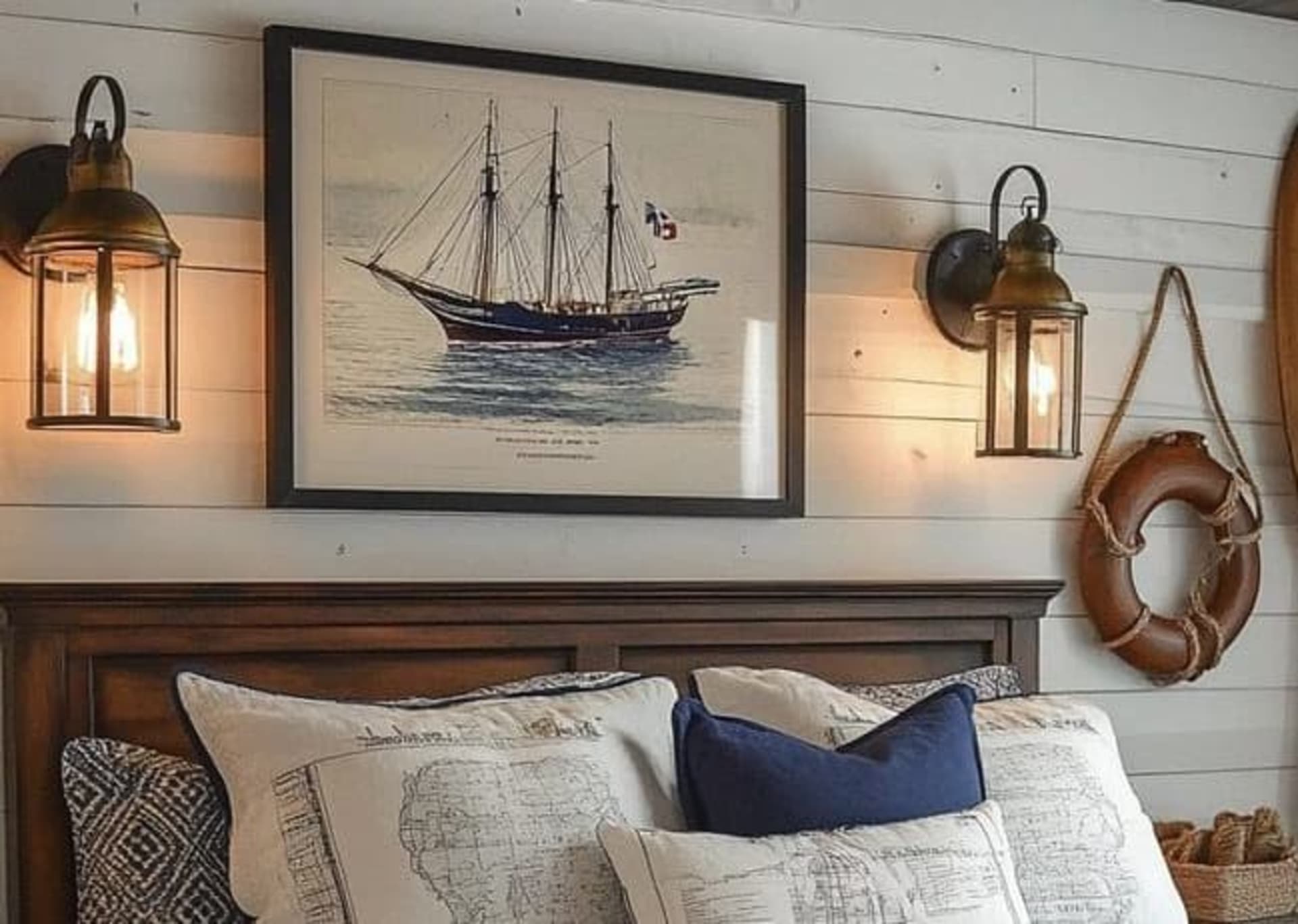 A coastal themed bedroom and bed with wall sconce lighting and sailor decor