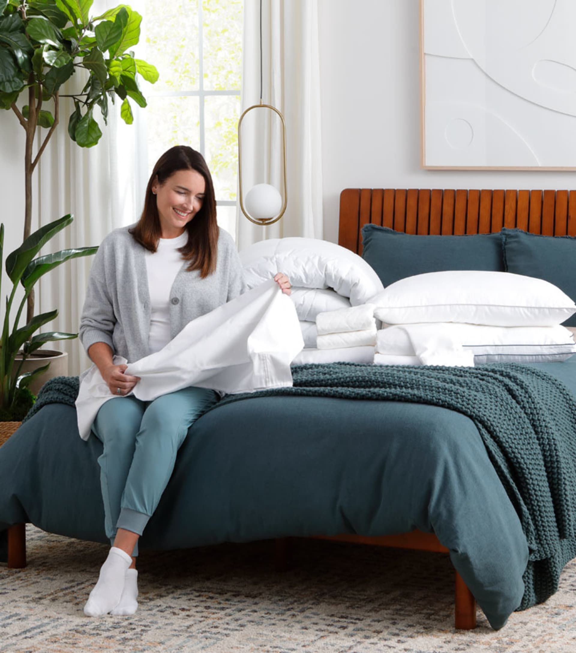 Woman Folding Sheets In Bedroom