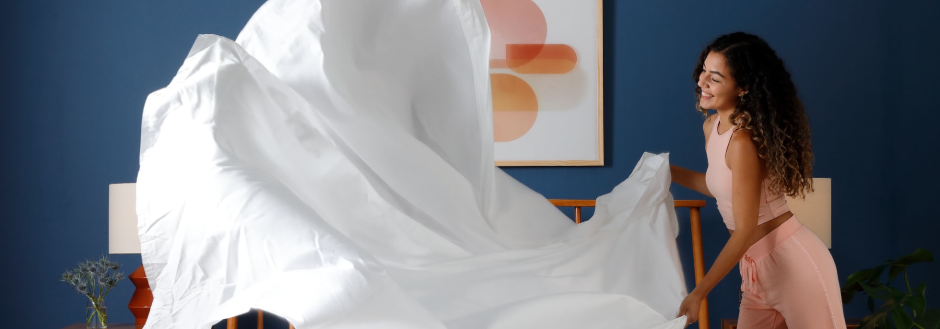 Woman making bed with top sheet