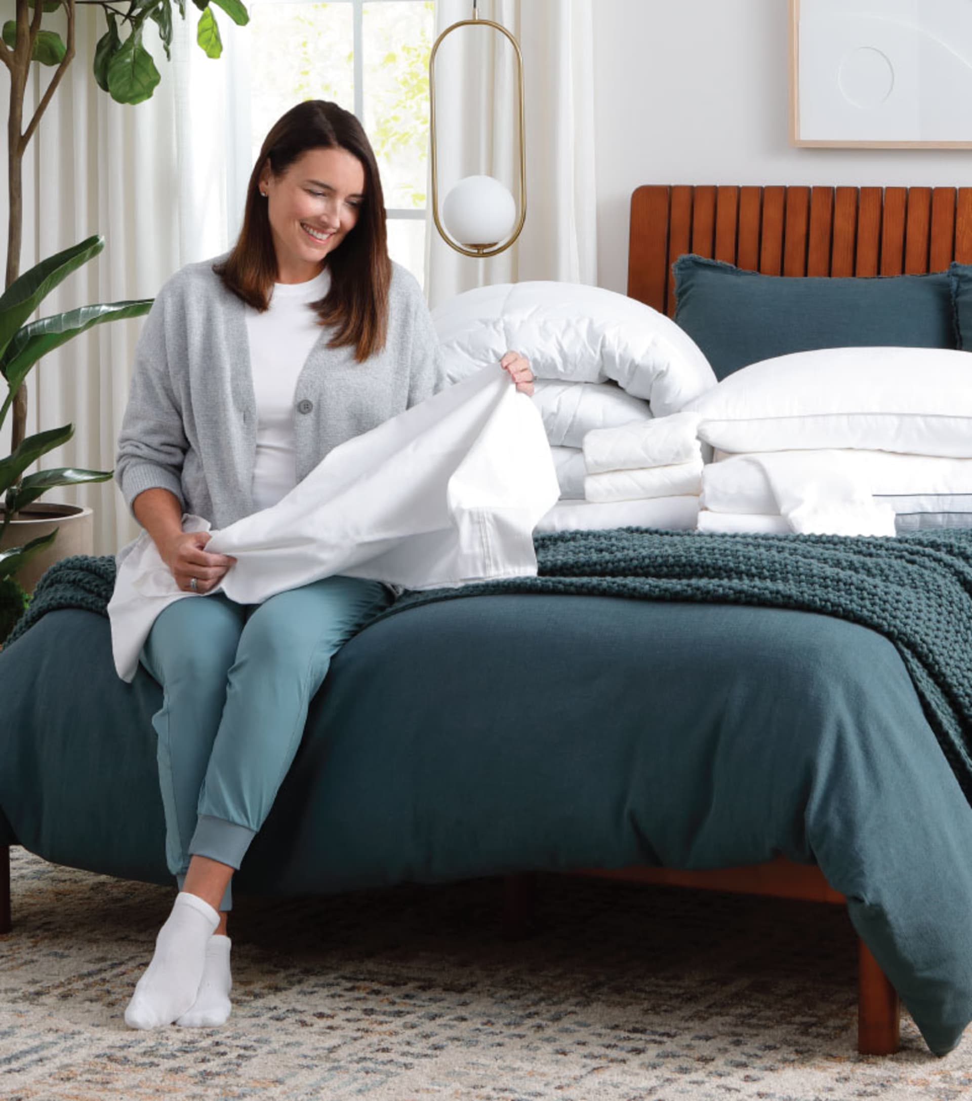 Woman holding sheets on bed