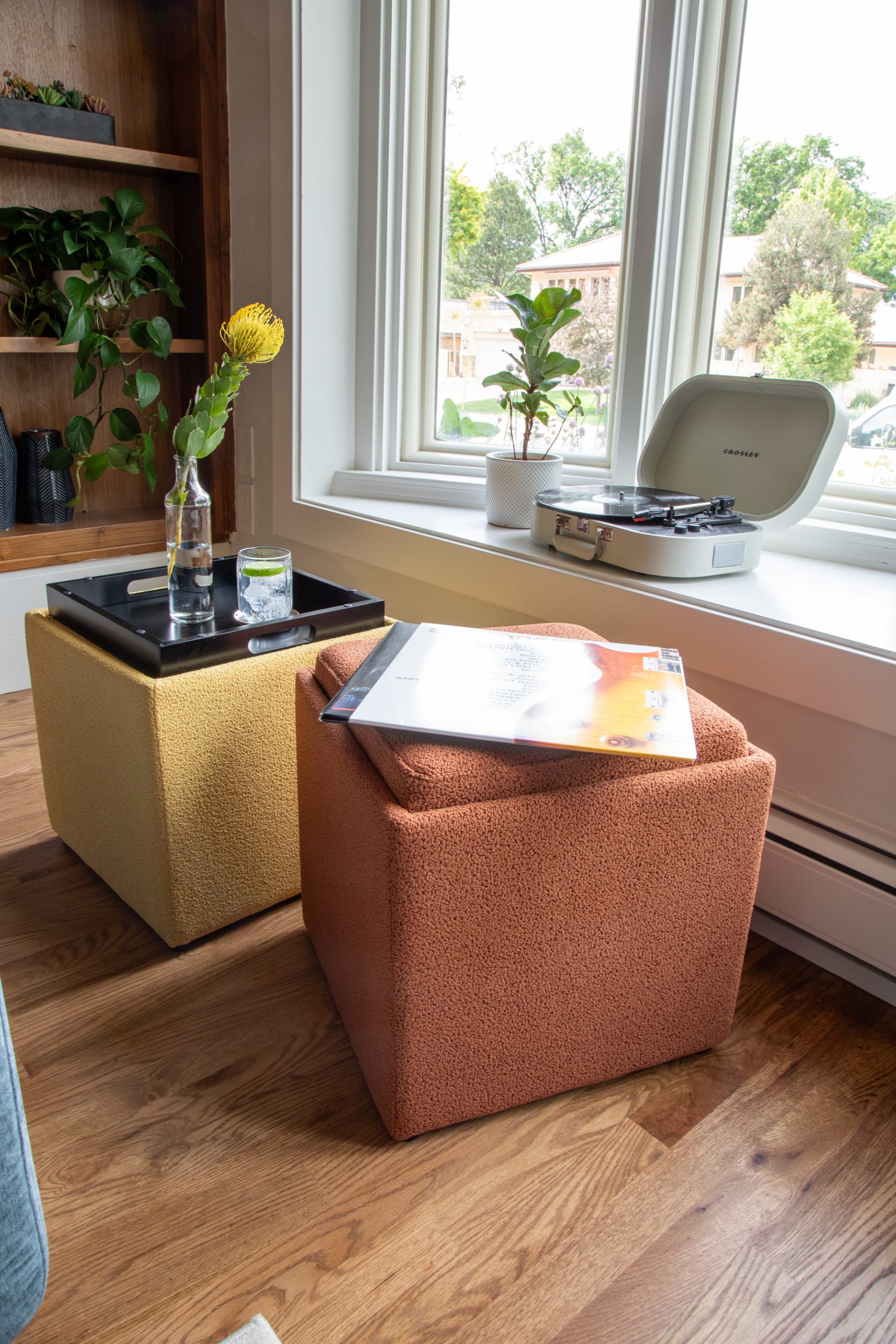 Yellow and orange storage ottomans in living room with records and record player