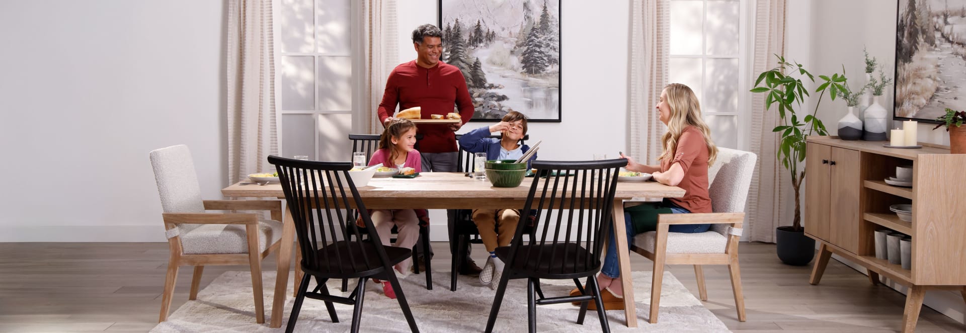 family eating at lIght colored dining set with black chairs in dining room