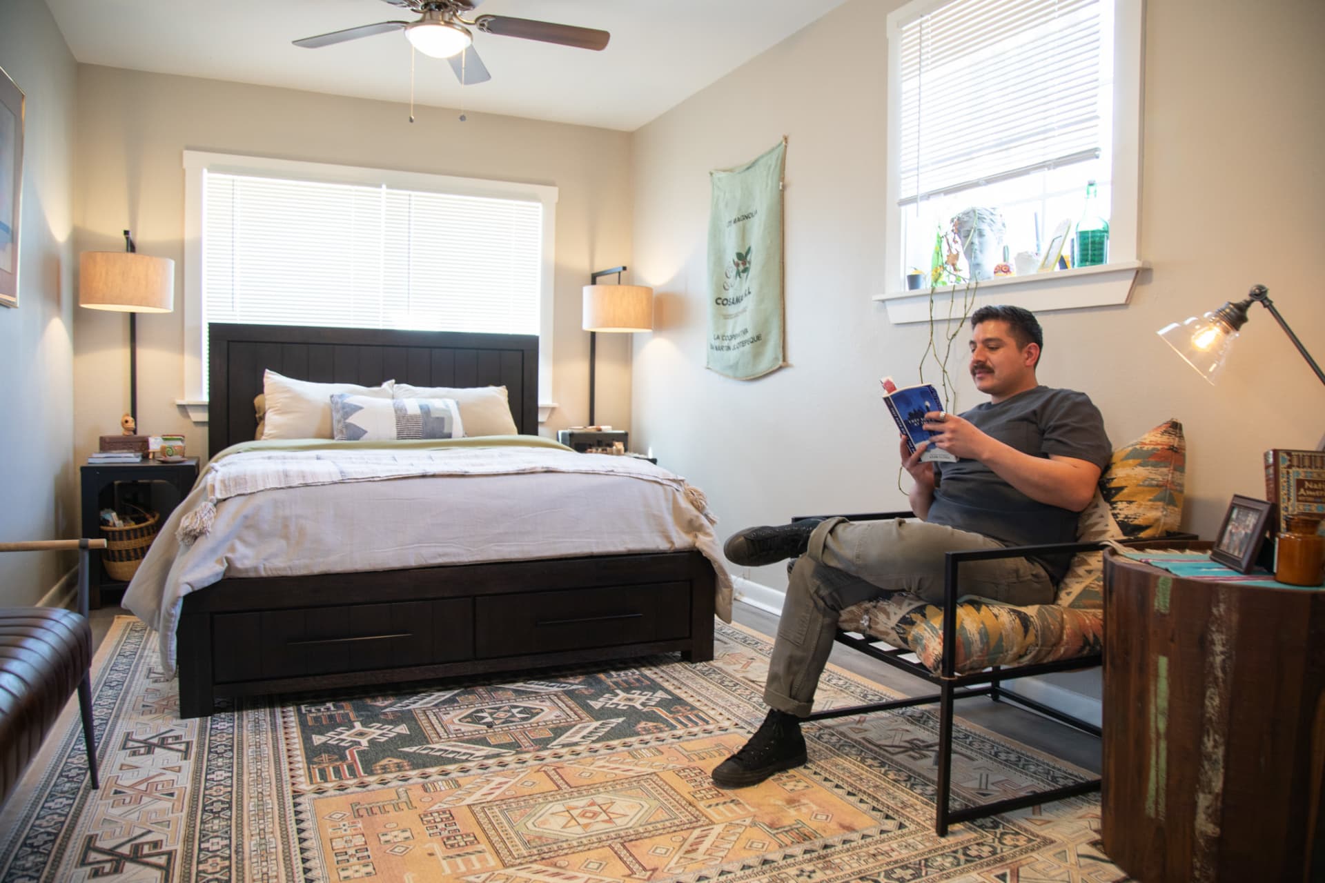 A Furniture Row employee reading a book by his bed in his bedroom