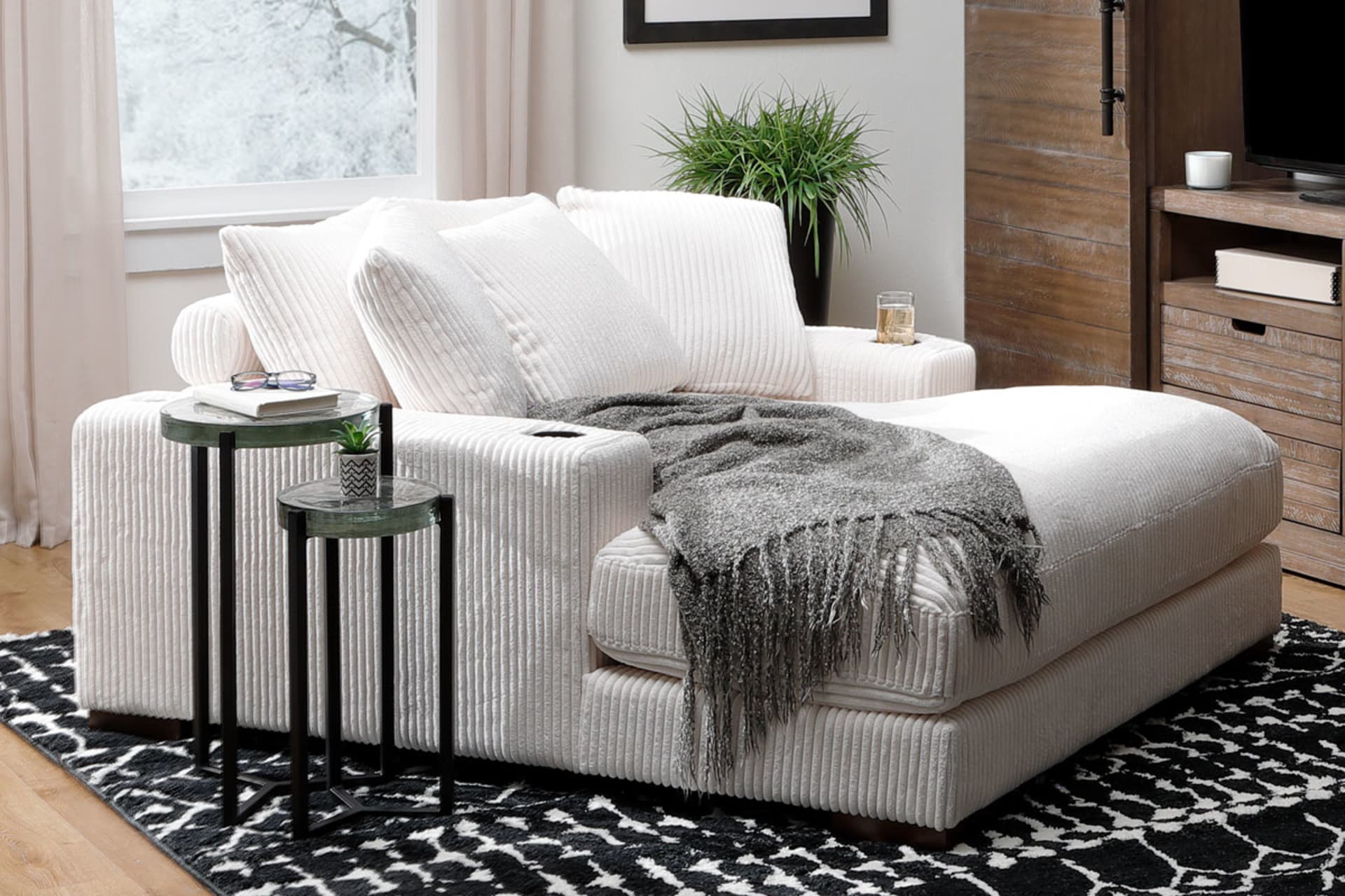 White Corduroy oversized lounge chair with cupholders in living room with entertainment center.