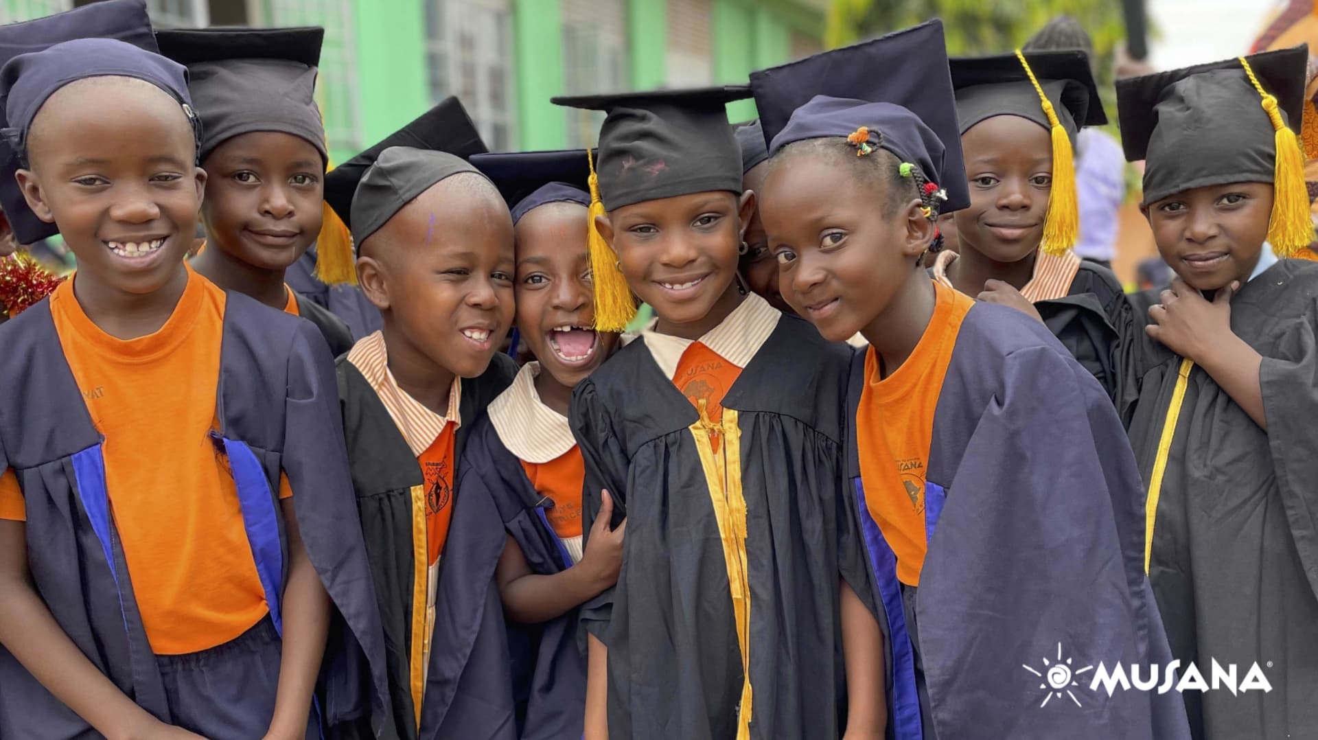 Kids with graduation hats smiling with Musana logo.