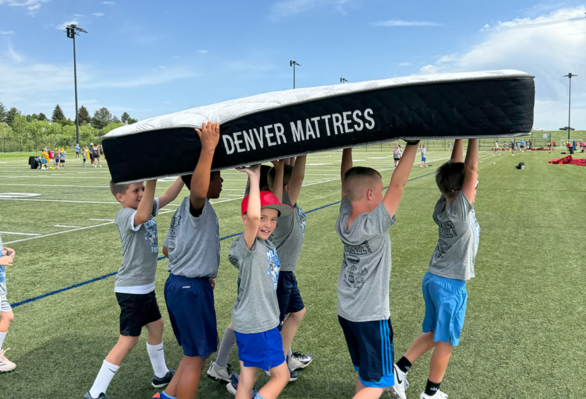 Kids holding up mattress on football field